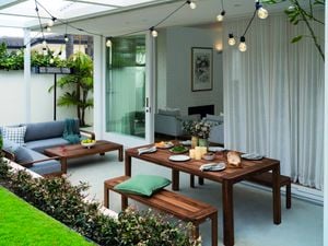 Lounge and dining setting placed outside with string bulb lights hung above