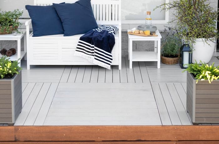 Outdoor entertaining area with white decking, planter boxes and chair.