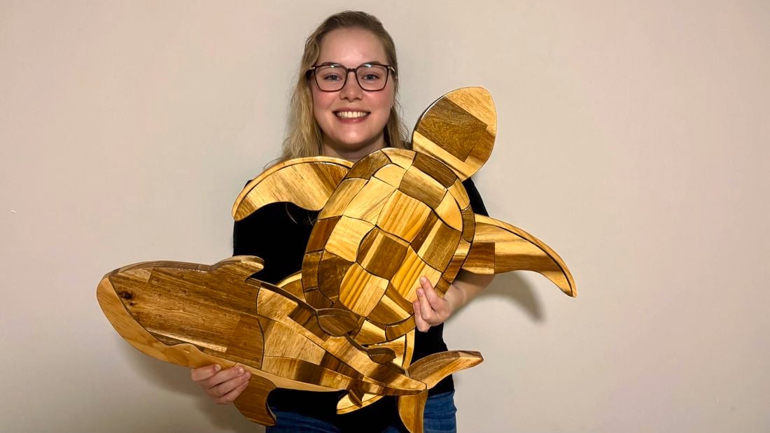 Alicia Clarke holding her woodwork designs.
