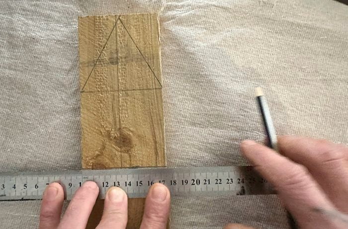 Hands holding a ruler and pencil, marking measurements on a small piece of timber.