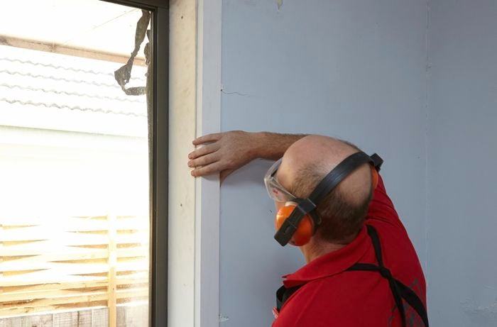 A person fitting architrave beside a window