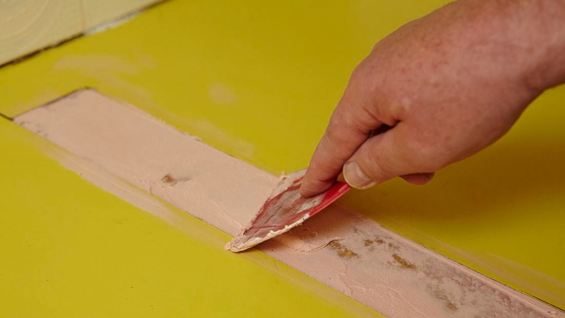 Person scraping putty into a gap.