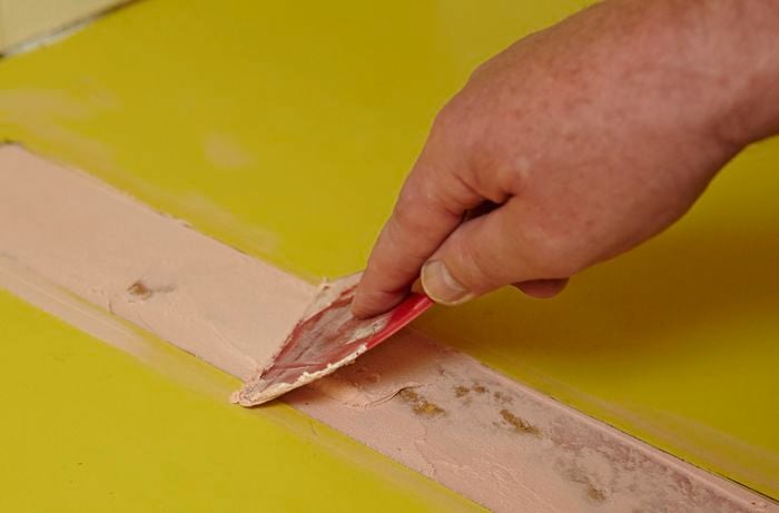Person scraping putty into a gap.