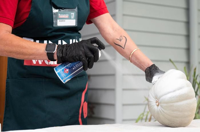 Bunnings team member spray painting the pumpkin.
