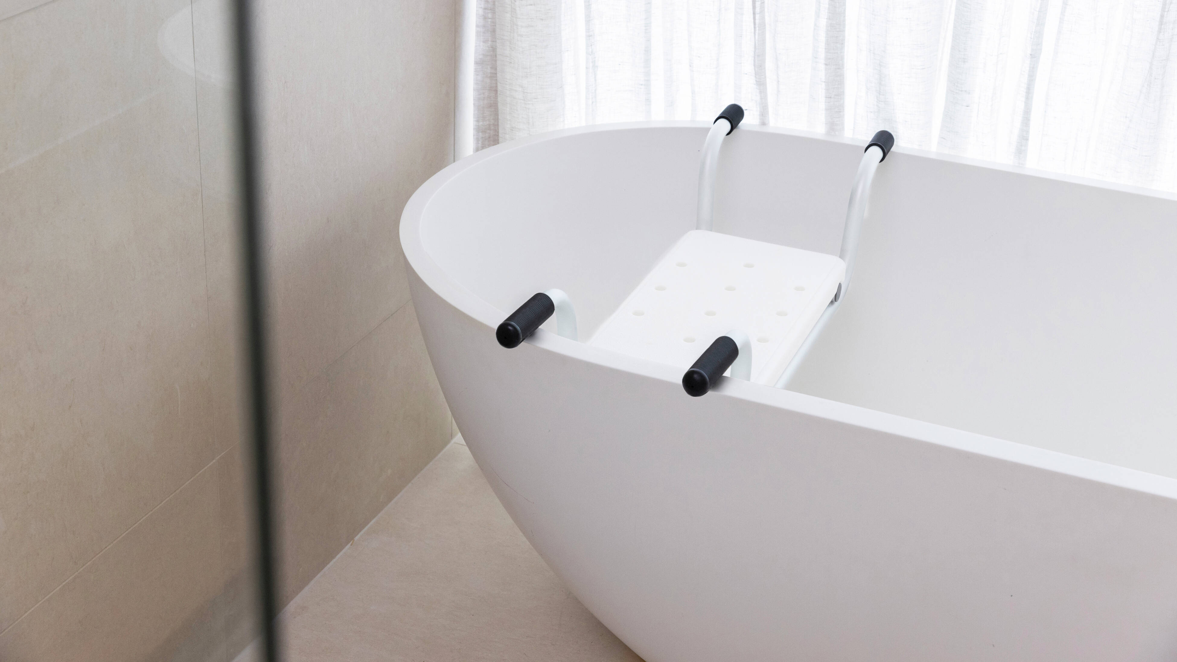 White bath with suspended assist chair hanging over the bath.