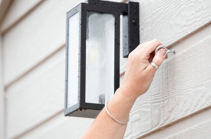 Person screwing an cup hook into a weatherboard wall