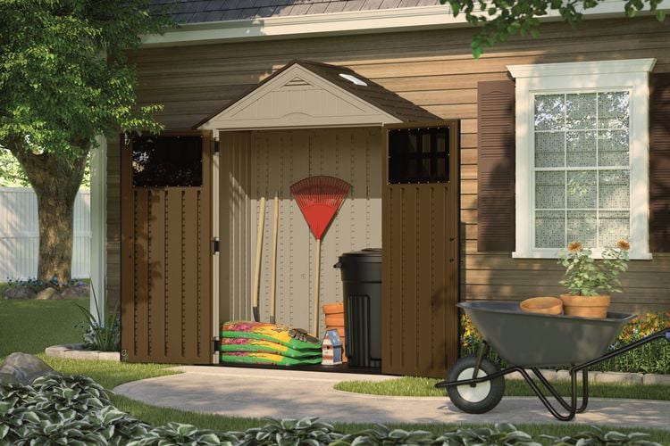 Storage cabinet against the external wall of a house containing garden tools and potting mix