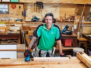 A builder in his workshop posing with a Makita sander wearing a hi-vis green shirt