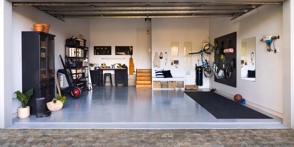 Wide shot of a garage makeover, featuring an epoxy floor, storage units and gym equipment