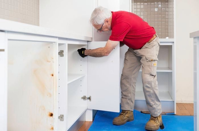 A Bunnings Team Member is removing a kitchen cabinet door.