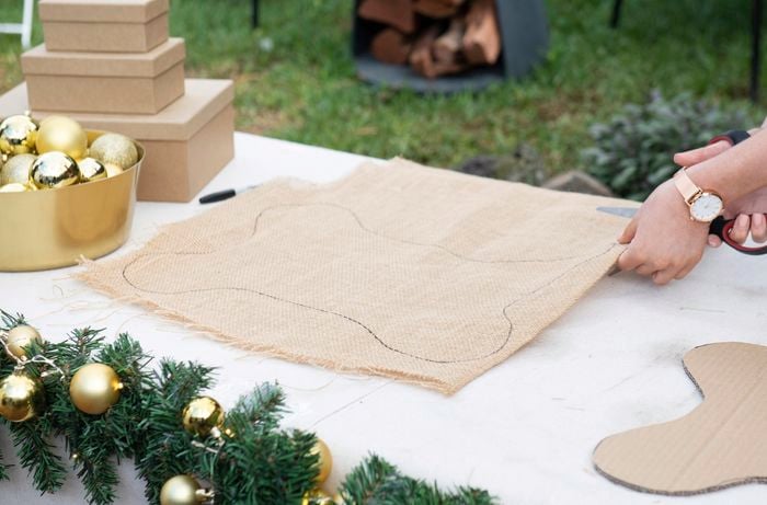 A person cutting through two sheets of hessian marked with the outline of a large bone