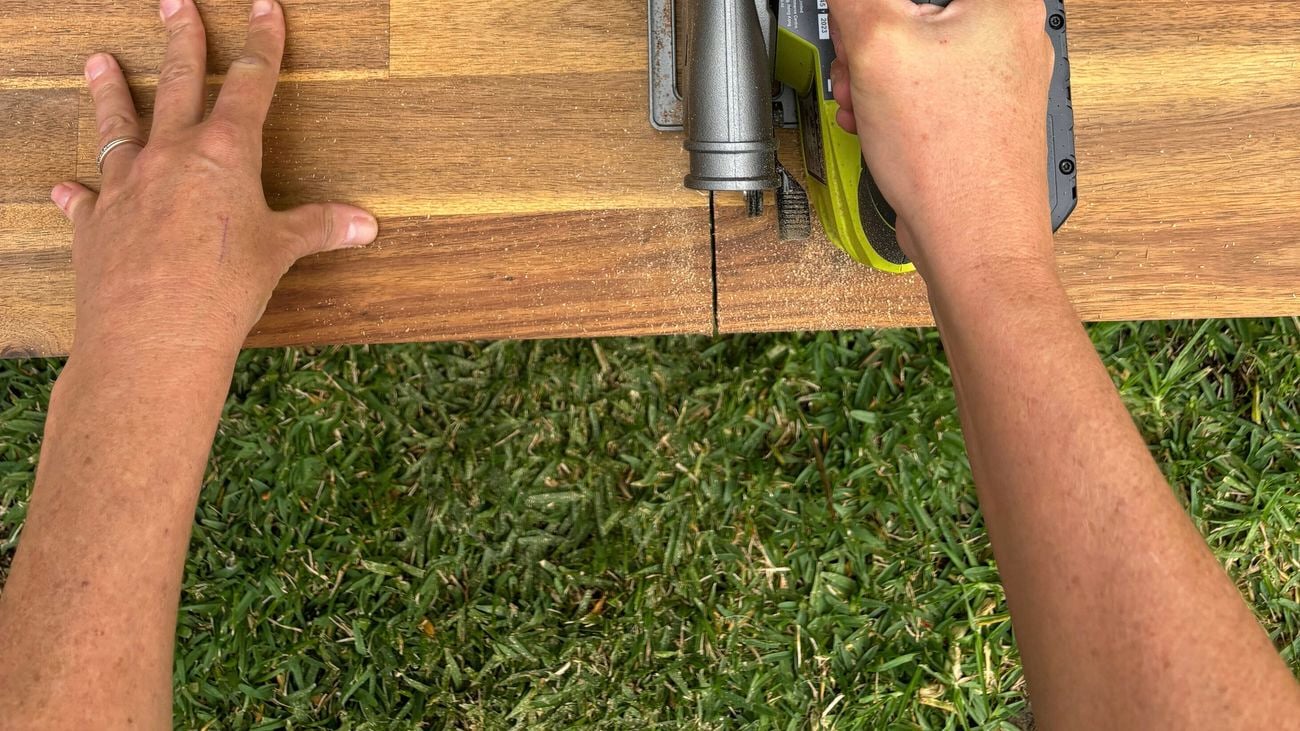 A pair of hands cutting a benchtop with a circular saw.