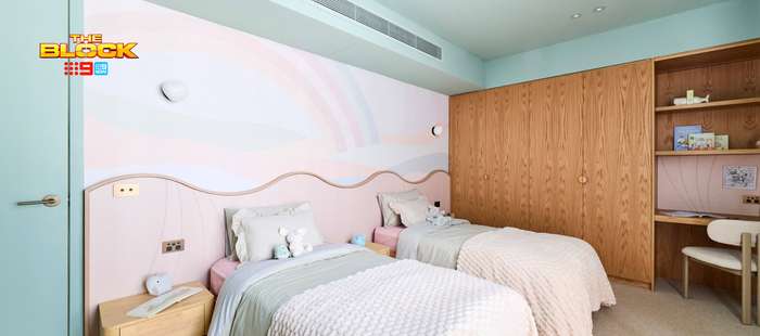 Contemporary twin bedroom featuring pastel bedding, a curved pink feature wall, timber wardrobes and a built-in study desk.