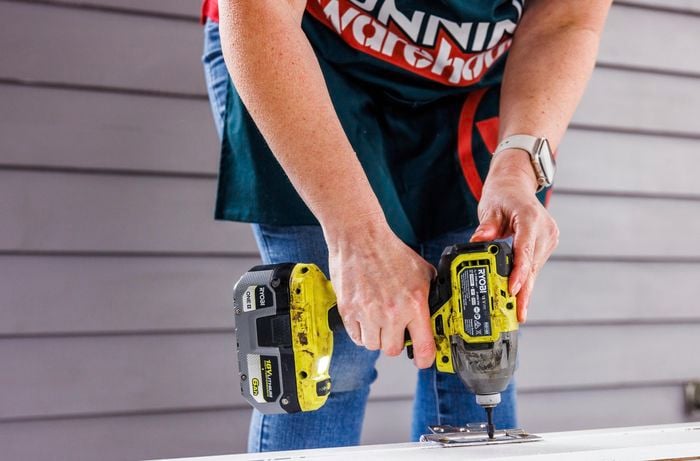 A person drilling the hinges.