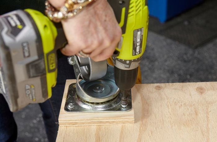 Castor wheels being screwed to a raised surface on the underside of a bed frame