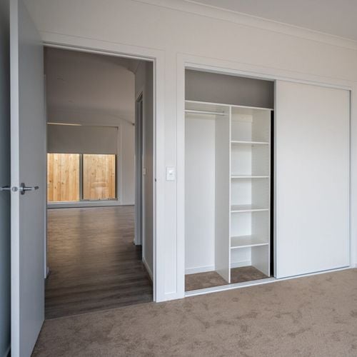 Inside of a bedroom with white cupboards and white shelving