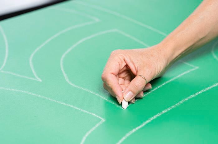 A person is drawing road outlines with a pencil and leaving space for buildings and open areas.