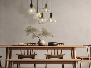 Wooden dining table and chairs underneath suspended decorative lights and bulbs