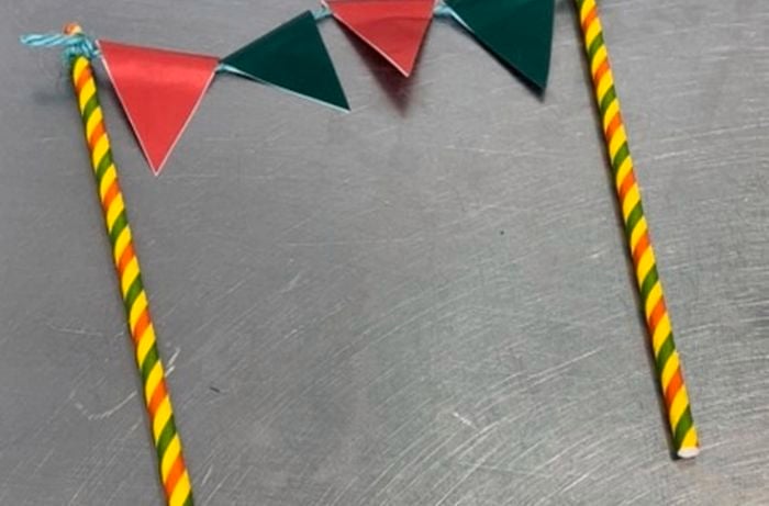 cake topper, two straws as post with string and triangle paper hanging in-between the straws