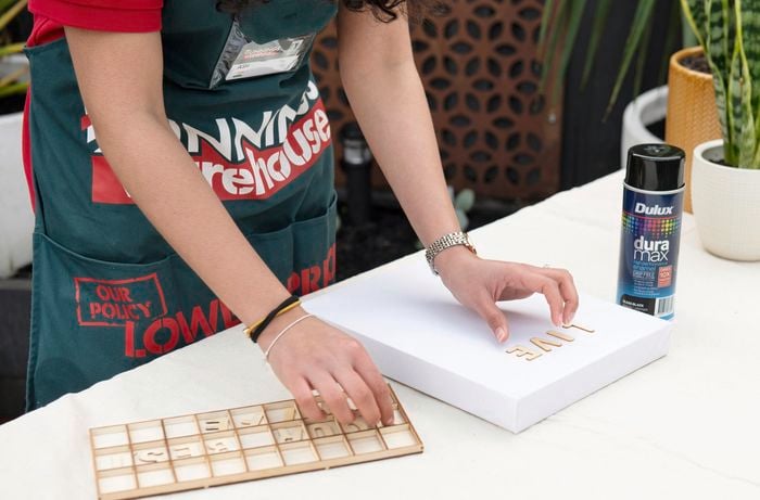 Person arranging wooden alphabet letters on a stretched canvas