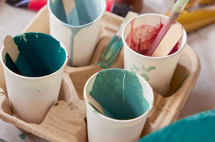 Cups of paint and paint tubes sprawled on a canvas
