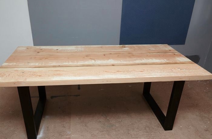 An assembled wooden dining table with black stained legs