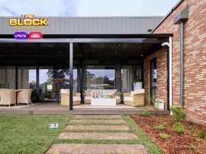 A backyard with paved steps, an outdoor setting and tables and chairs on a decking.