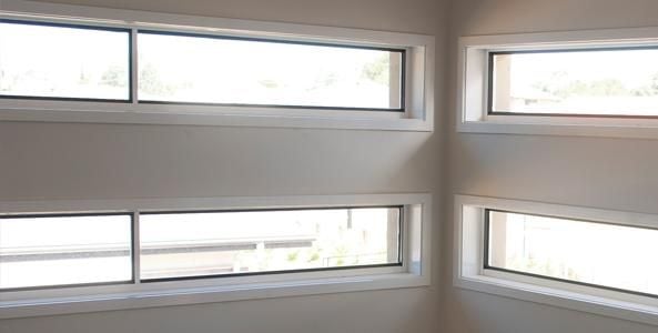 Interior view of a white room with four narrow horizontal windows 