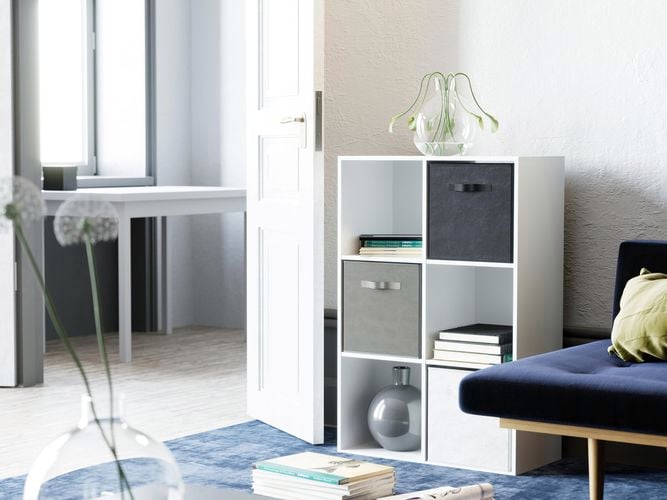 A cube shelving unit, a chair and a rug in a room