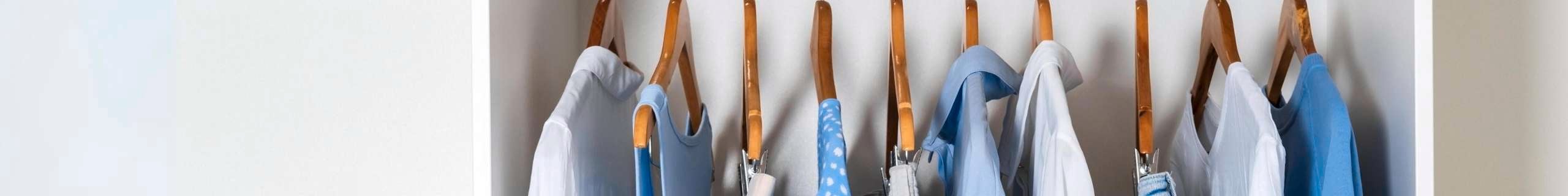 Clothes hanging on hangers in a wardrobe.