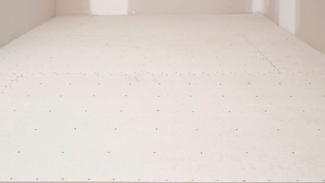 Underlay sheets are installed and evenly nailed to the floor   Image Description: The image shows a room with underlay sheets securely fastened to the floor using evenly spaced nails.