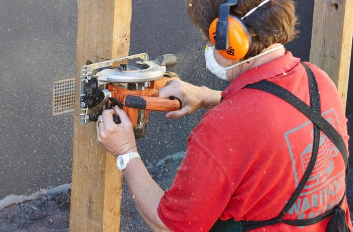 Person using power sander on timber plinth.