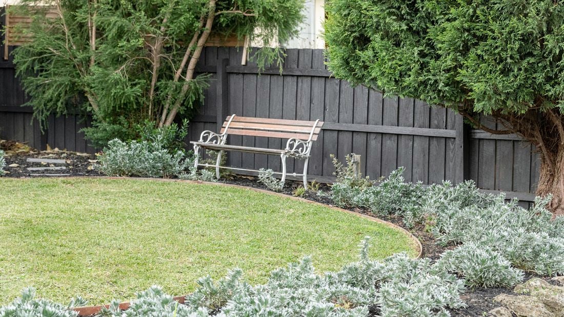 Park-style bench sitting at the edge of a front yard