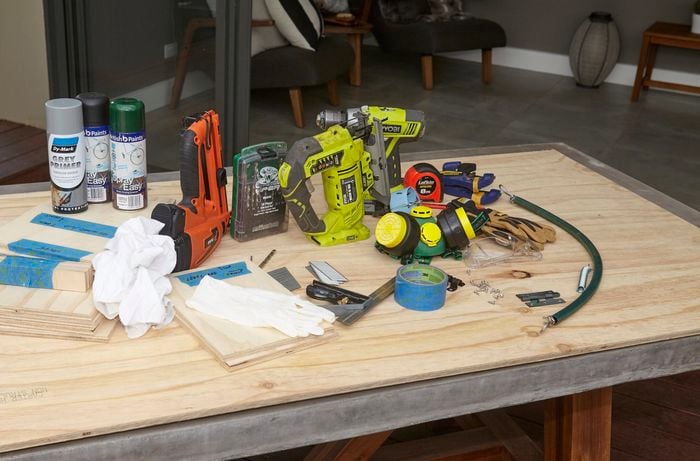 All the tools and materials required for the job, including paint cans, power drills, jigsaw, nail gun, respirator mask, pieces of timber and more