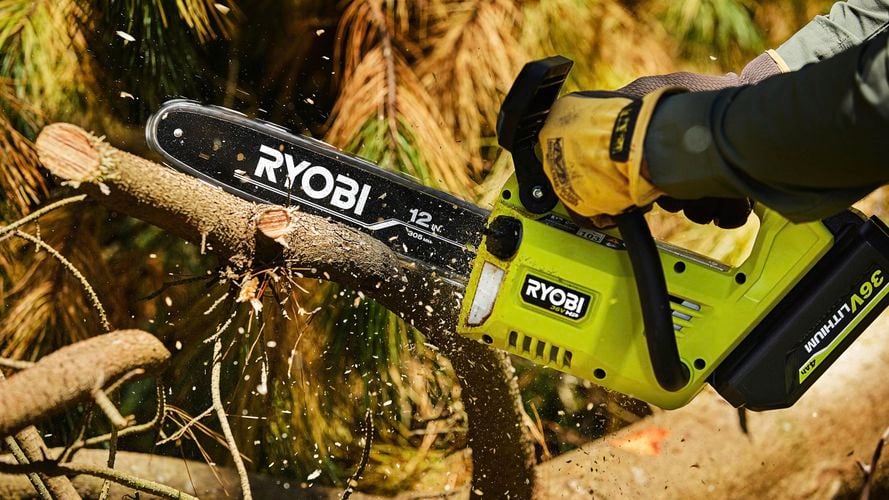 A person using a chainsaw to cut a branch.