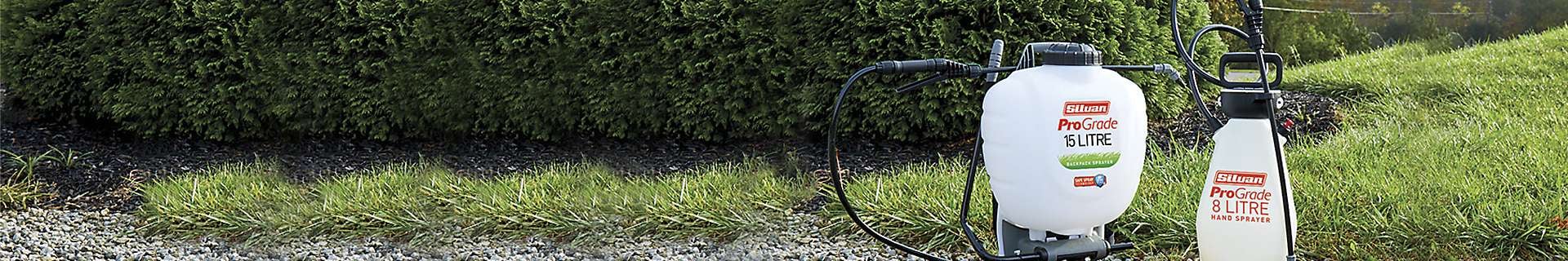 Garden with garden sprayers sitting on a bed of pebbles.
