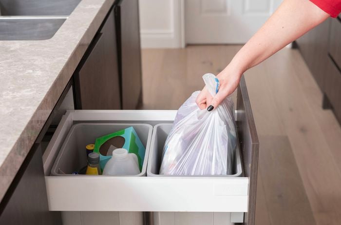 A hand is cleaning the bins by taking out the trash to get rid of smelly bins.