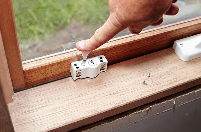 A person pushing down on the bolt of a window lock