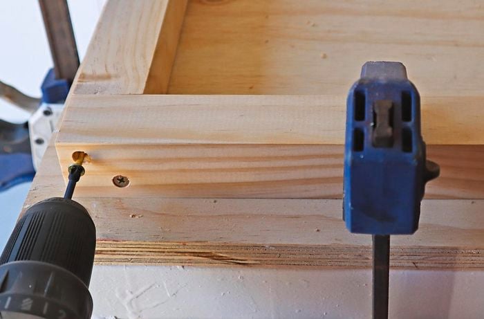 The frame of an office desk being screwed into place