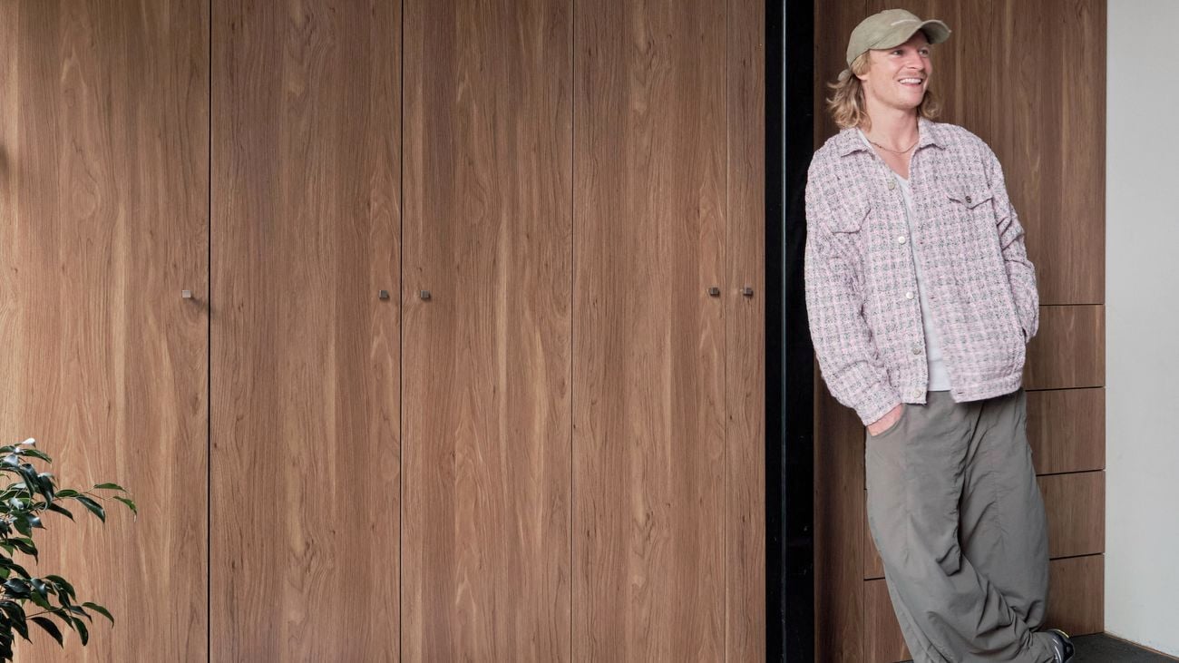 A man leaning against a pole in front of timber-look wardrobe