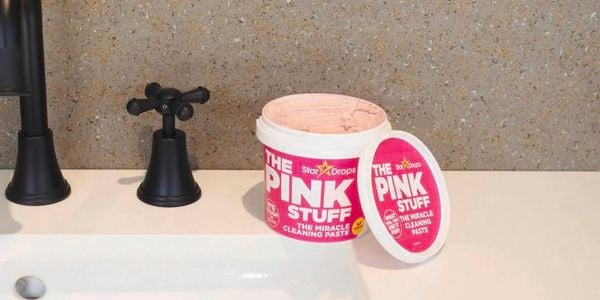 A tub of The pink stuff on a sink with black tapware.