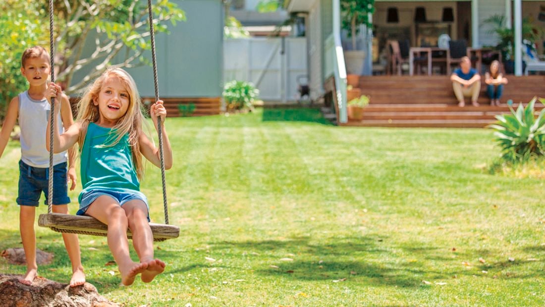 Children playing on a swing with the lawn well maintained