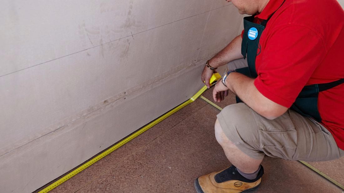 A bare floor being measured by a Bunnings team member with a tape measure