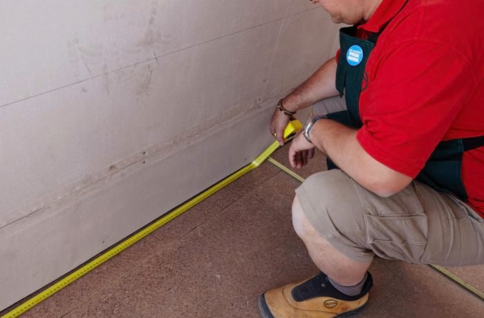 A bare floor being measured by a Bunnings team member with a tape measure