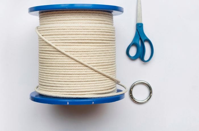 A person attaching a metal ring using cotton rope