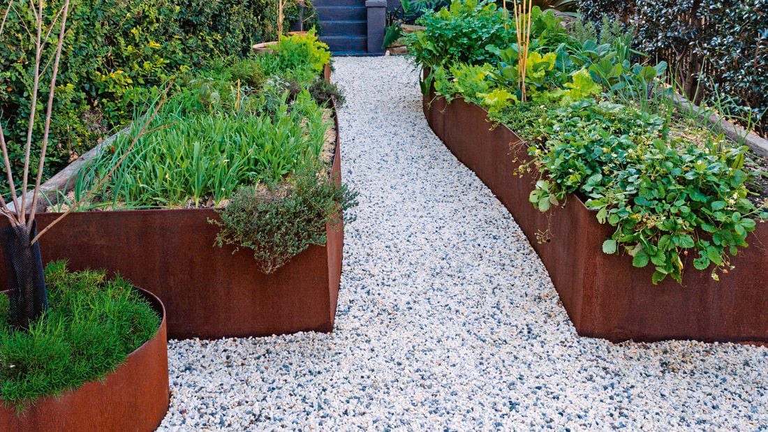 Pathway of stone to home with planter boxes laid out in yard