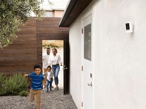 Family with children playing down the side of a house