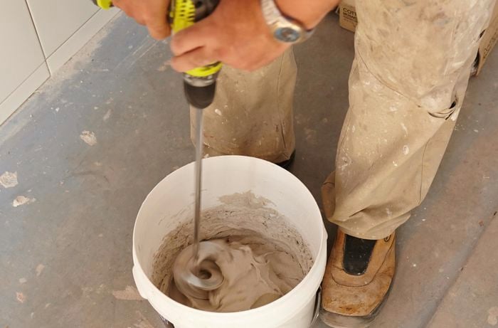 Tile adhesive being mixed in a bucket using a power mixing paddle