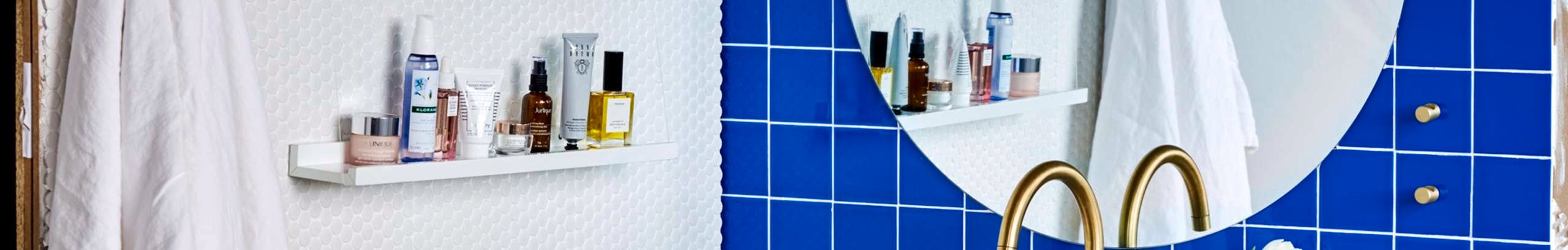 Renovated bathroom with blue wall tiles, gold tapware and decorative items.