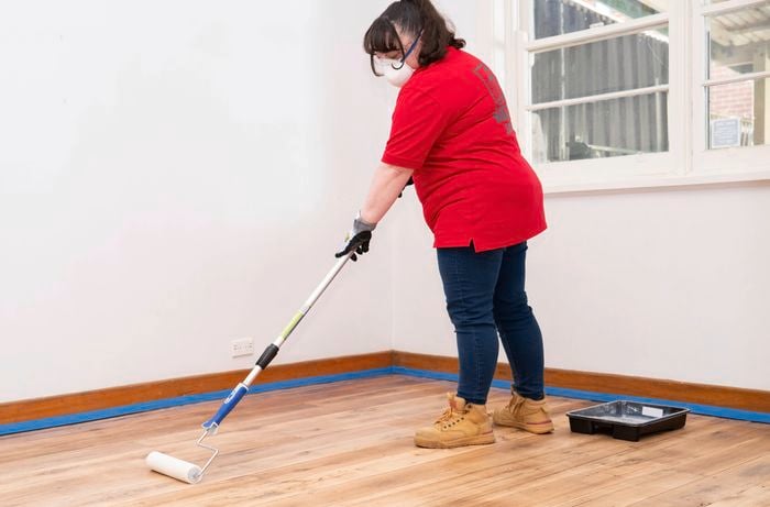 A Bunnings Team Member is applying floor sealer with a roller in even strokes to create a smooth finish.​​ 